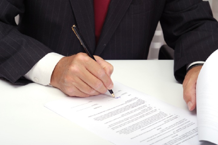 Businessman with black pen signing contract.